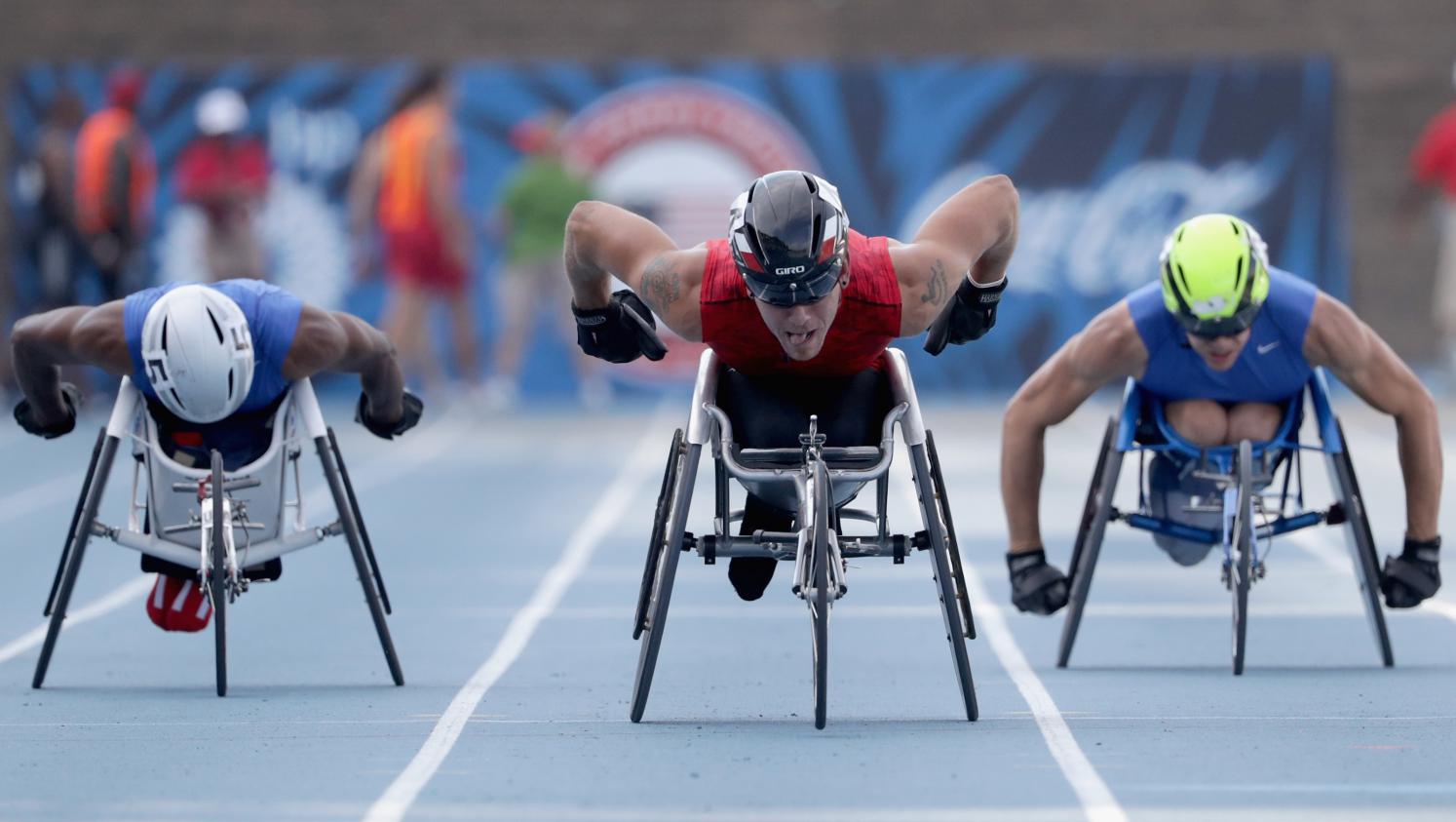 Trois athlètes en fauteuil roulant sur une piste d'athlétisme