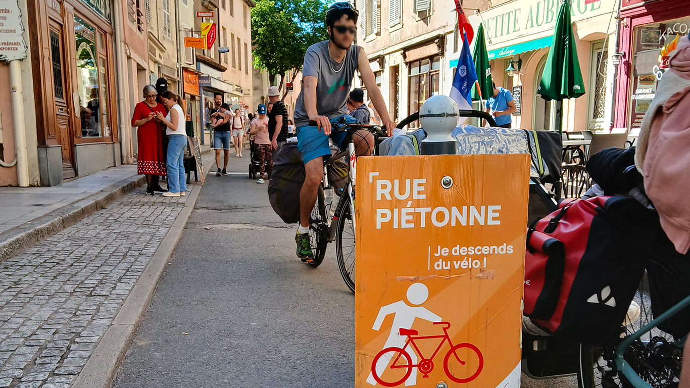 Rue piétonne avec un panneau orange : "Je descends du vélo"